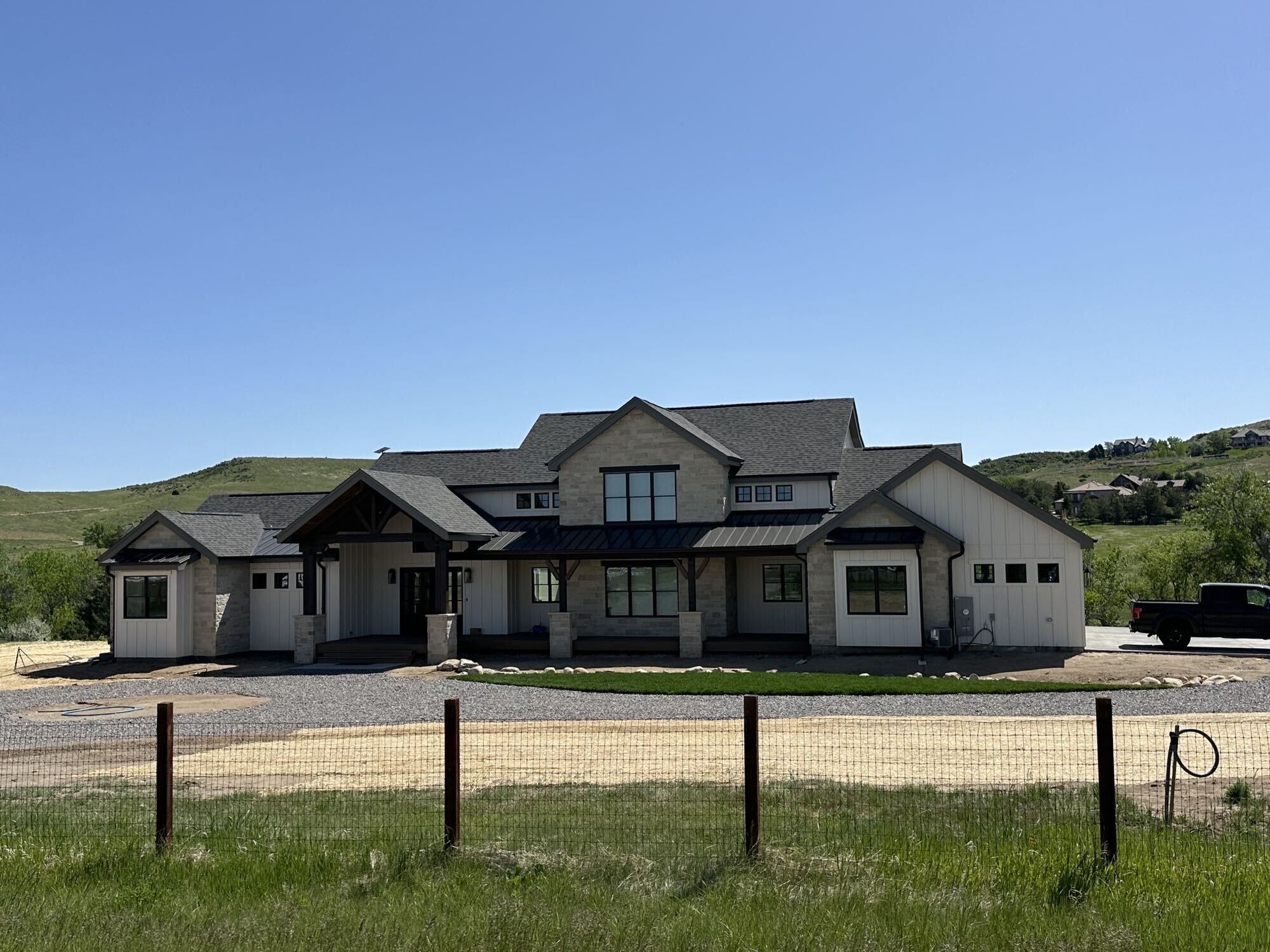 Custom hillside home with stone details, metal roof accents, and wide front porch